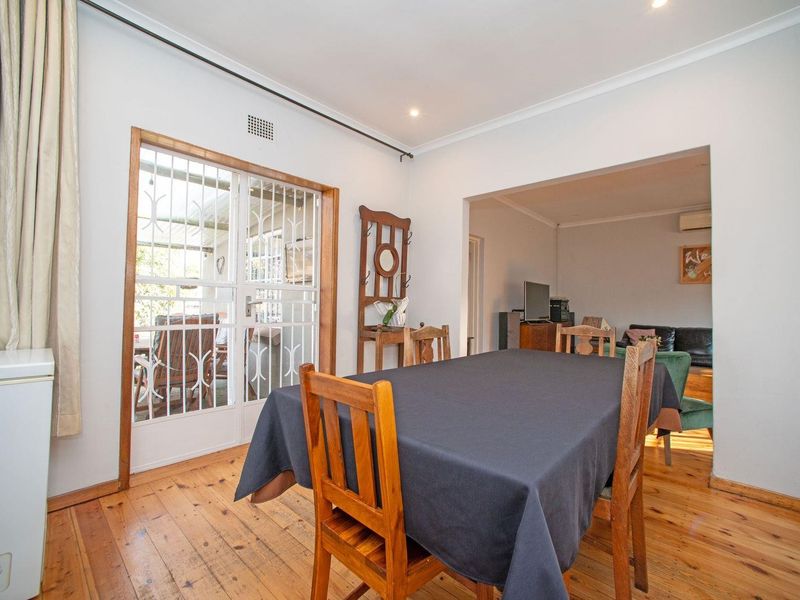 Open plan dining area featuring timber flooring, recessed lighting, and a security gate leading to the outdoor patio space.