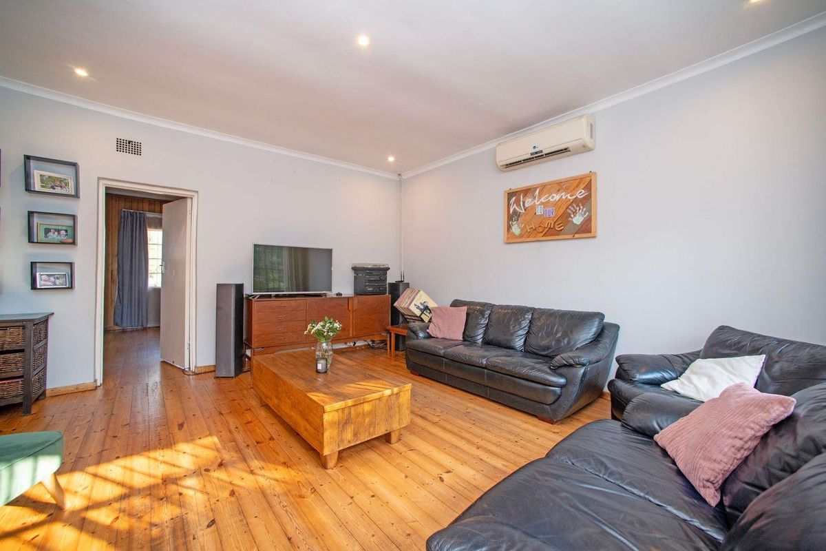 Spacious living room featuring polished hardwood flooring, recessed downlighting, and a wall-mounted air conditioning unit.