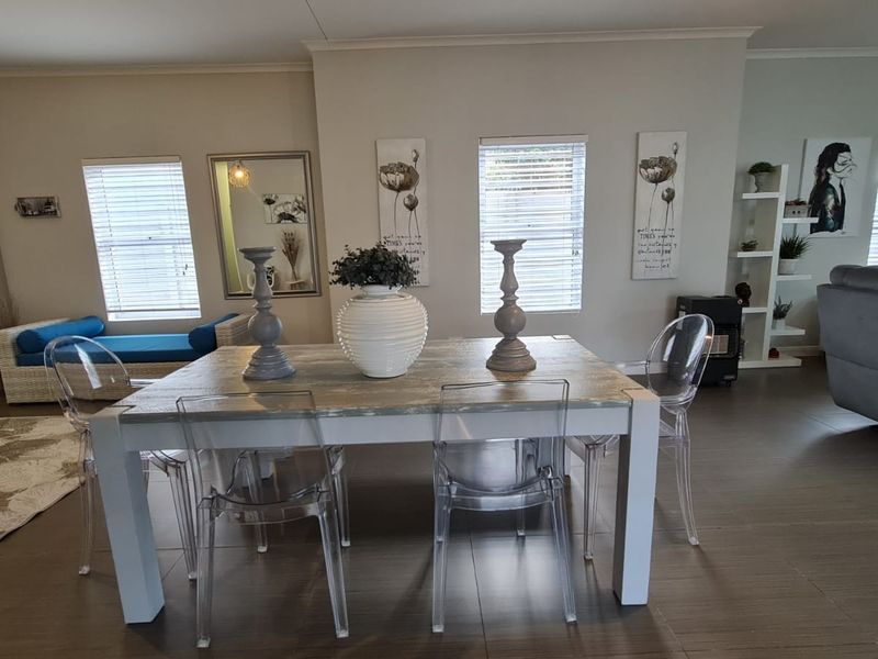 Spacious open-plan living and dining area featuring neutral wall tones, tiled flooring, and built-in shelving units.