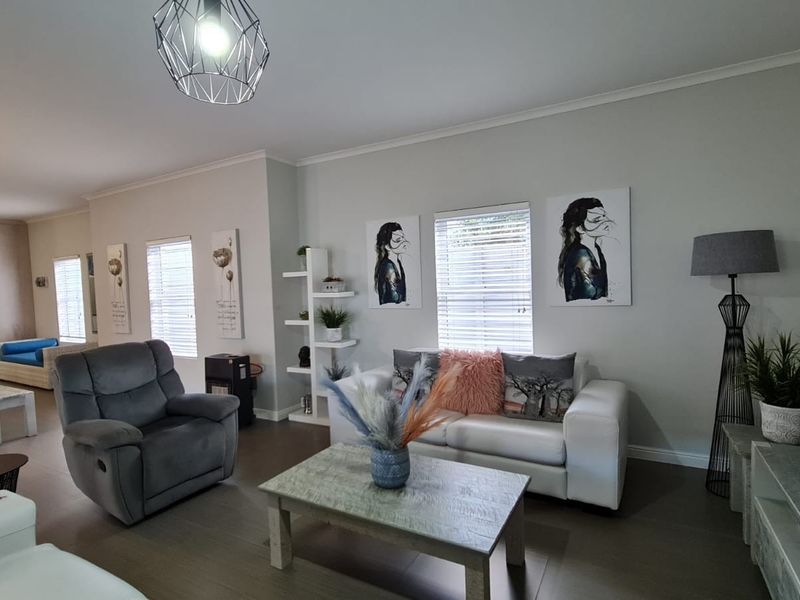 Spacious open-plan living area featuring modern laminate flooring, neutral wall tones, and integrated kitchen space with contemporary lighting fixtures.
