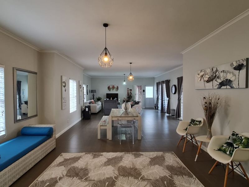 Spacious open-plan living and dining area featuring large format floor tiles, modern pendant lighting, and neutral wall finishes throughout.