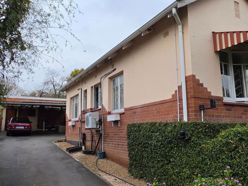 Side view of the house showing the brick and plaster facade, driveway access, and exterior air conditioning unit.