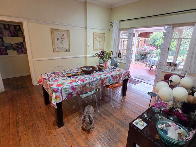 Dining room featuring original hardwood flooring and sliding glass doors providing direct access to the rear patio and garden area.