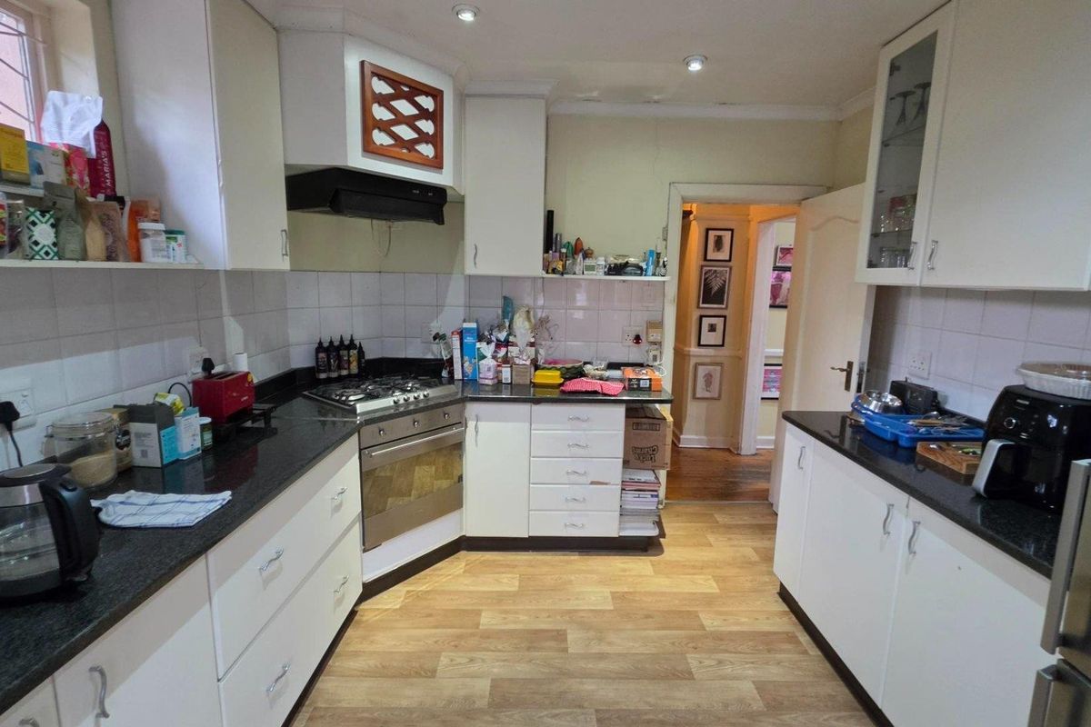 Functional kitchen featuring white cabinetry, dark granite countertops, gas hob, and integrated oven with tiled backsplash and wood-look flooring.