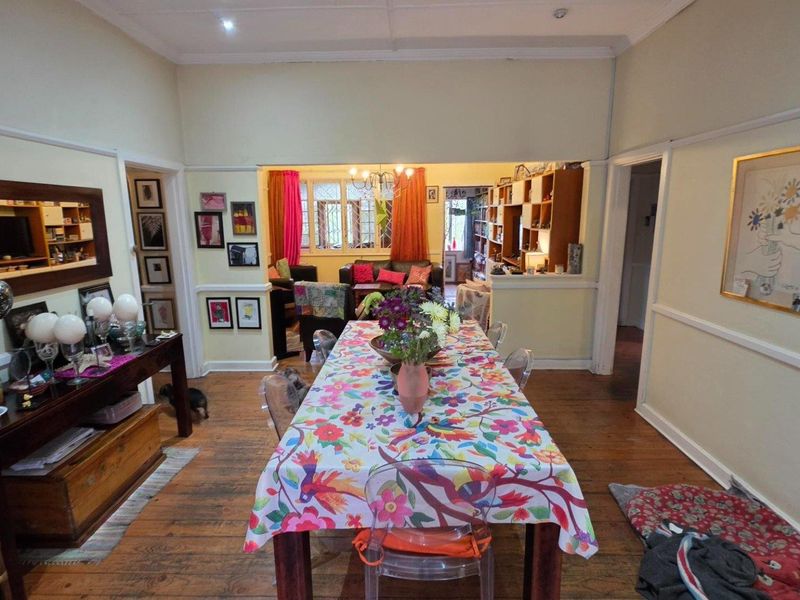Spacious open-plan dining and living area featuring original hardwood flooring, classic picture rails, and coved cornicing, creating a warm and inviting atmosphere.