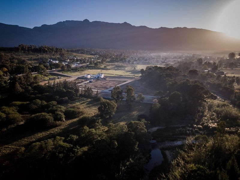 An aerial view of the property location, showcasing the surrounding landscape, natural terrain, and access roads with mountain views in the distance.