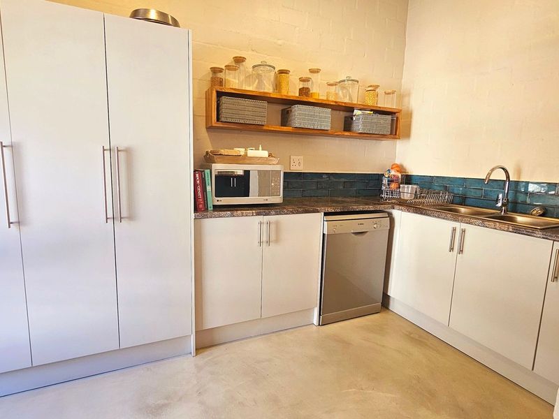 A functional scullery featuring white cabinetry, laminate countertops, a stainless steel sink, subway tile backsplash, and integrated dishwasher.