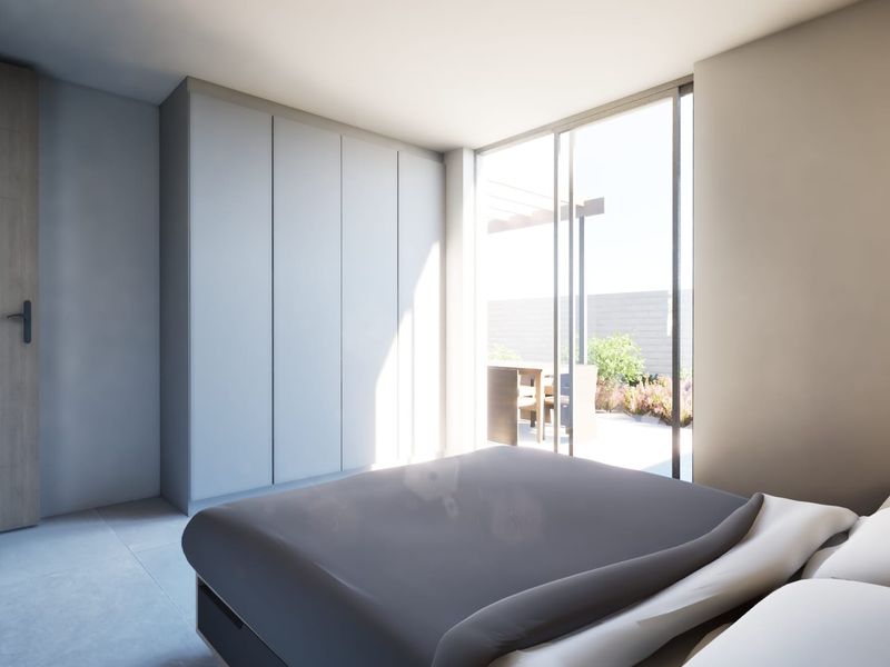 Modern bedroom featuring built-in cupboards, tiled flooring, and large sliding glass doors providing direct access to an outdoor patio area.