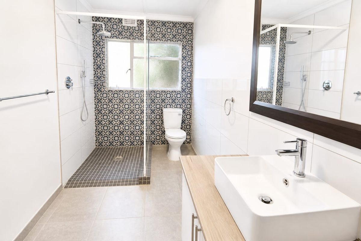 Modern bathroom featuring a walk-in shower with decorative patterned tiling, a vessel sink vanity, and a clean, minimalist aesthetic.