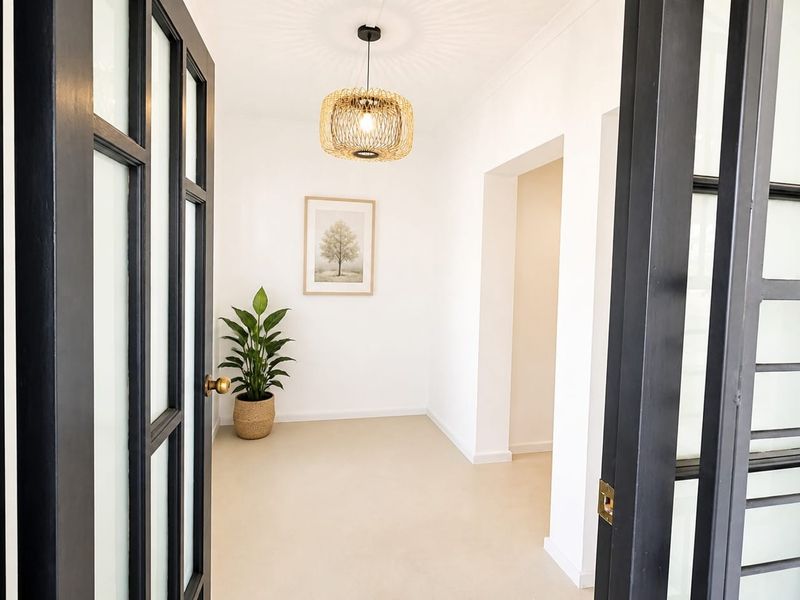 A bright and welcoming entrance hall featuring elegant black-framed french doors and clean, neutral finishes.