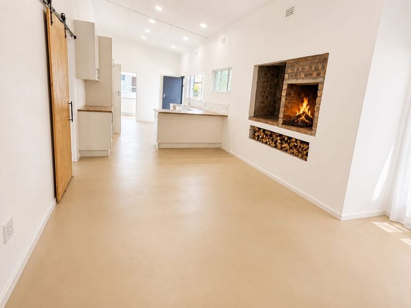 Spacious open-plan living and kitchen area featuring a built-in brick fireplace, wood storage niche, modern cabinetry, and a sliding barn door.