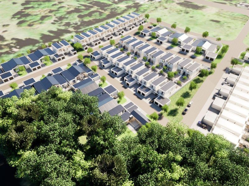 An aerial view of a modern townhouse development featuring multiple residential units, paved internal roads, and landscaped surroundings.