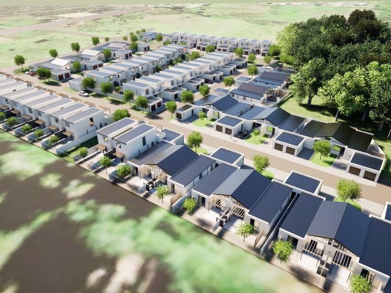 An aerial perspective of a modern townhouse development featuring multiple residential units, paved access roads, and landscaped communal areas.