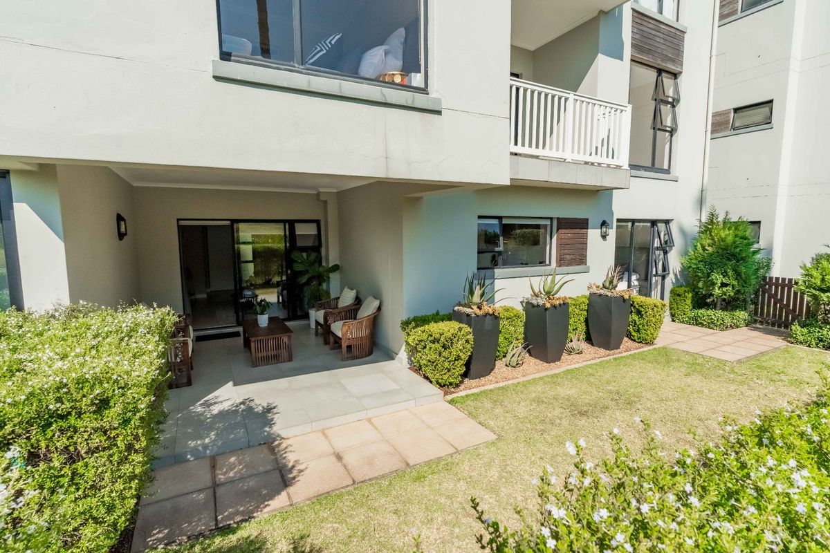 A ground-floor apartment featuring a covered tiled patio, sliding door access, and a well-maintained private garden area.