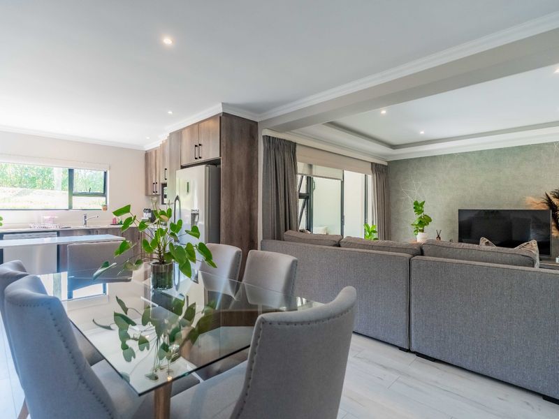 Modern open-plan living area featuring a contemporary kitchen with built-in cabinetry, a dining space, and seamless flow to the lounge with sliding door access.