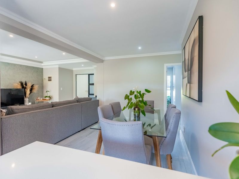 A bright open-plan living and dining area featuring modern laminate flooring, recessed downlighting, and neutral wall finishes.