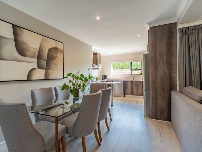 Modern open-plan living and dining area featuring light laminate flooring, recessed lighting, and a functional kitchen with contemporary cabinetry.