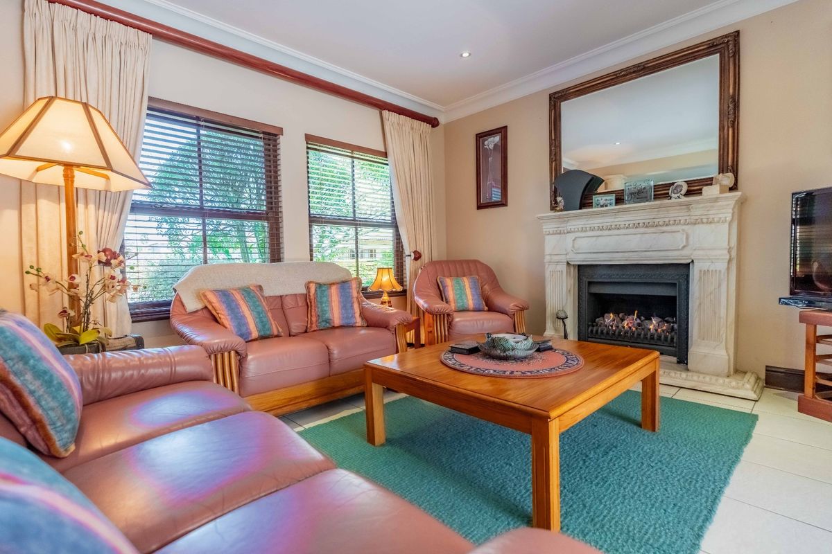 A comfortable living room featuring a classic fireplace with a decorative mantelpiece, tiled flooring, and crown molding, creating a warm and inviting atmosphere.