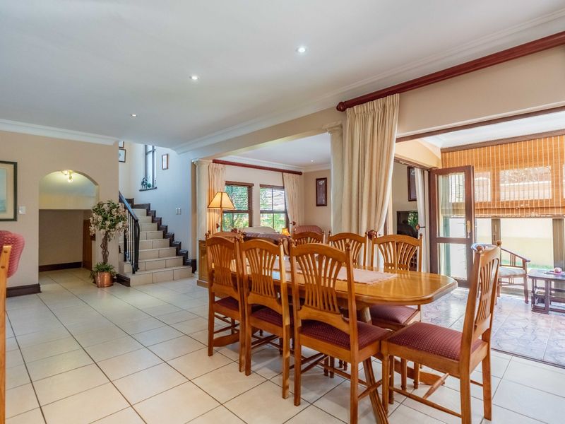 Spacious open-plan dining area featuring tiled flooring, recessed lighting, and direct access to an outdoor patio through sliding glass doors.