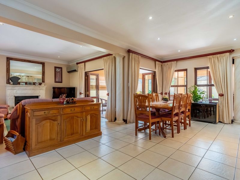 Spacious open-plan living and dining area featuring tiled floors, a classic fireplace, and multiple sets of french doors leading to the outdoor patio.