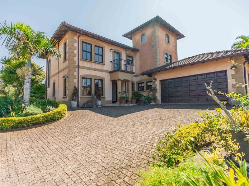A well-maintained double-story residence featuring a cobblestone driveway, double garage, and classic stucco exterior with a balcony.