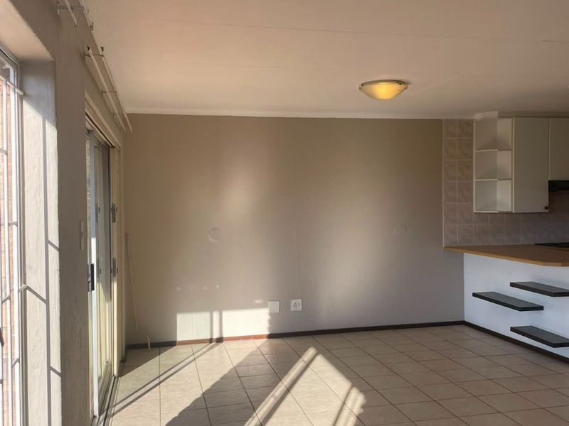An open-plan living and kitchen area featuring tiled flooring, a breakfast bar, and large sliding glass doors providing natural light.