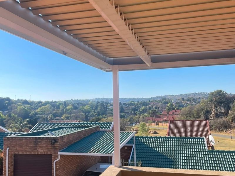 A covered balcony featuring a louvred roof and solid balustrade, offering elevated views over the surrounding residential neighbourhood.