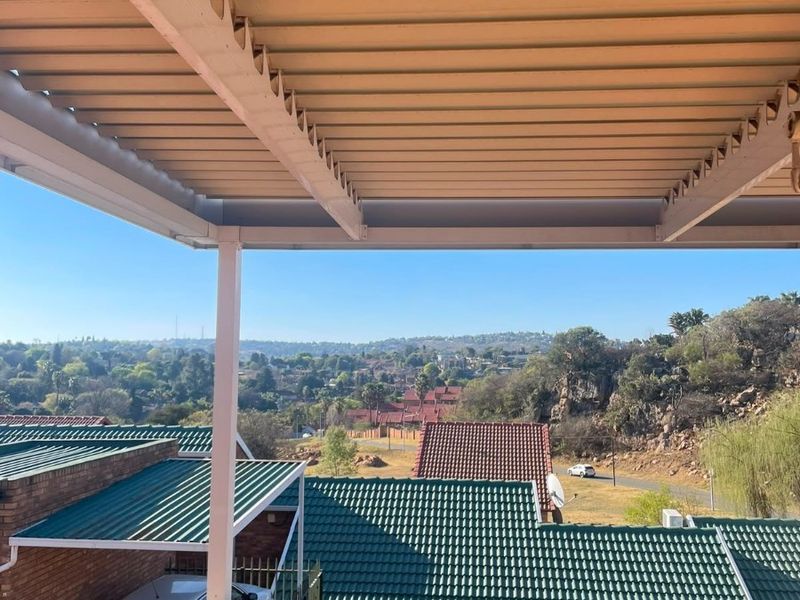 A covered balcony area featuring a corrugated metal roof and solid balustrade, offering elevated views over the surrounding residential neighbourhood.