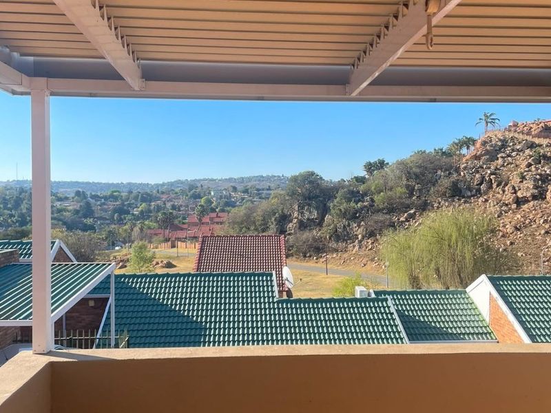 A covered balcony featuring tiled flooring and a balustrade, offering elevated views of the surrounding landscape and neighborhood.