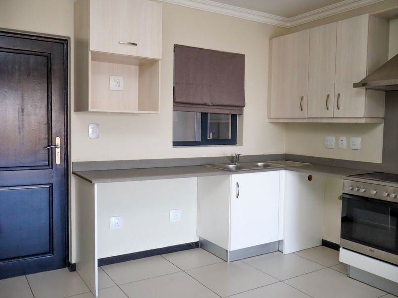 A clean, functional kitchen featuring light-toned cabinetry, stainless steel appliances, tiled flooring, and ample counter space for meal preparation.
