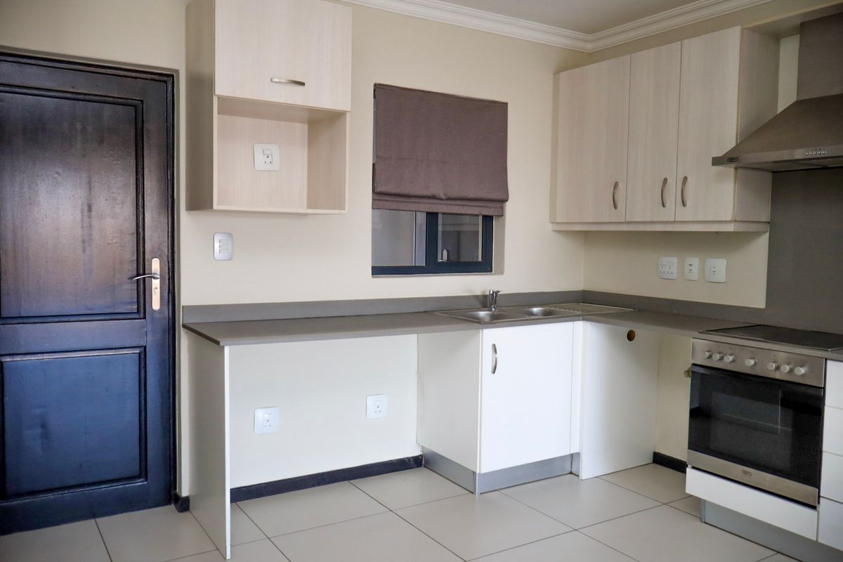 A clean, functional kitchen featuring light-toned cabinetry, stainless steel appliances, tiled flooring, and ample counter space for meal preparation.