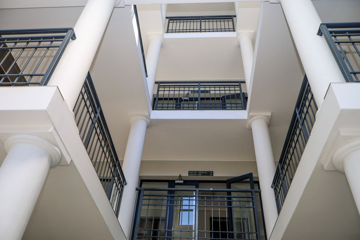 A view looking up through the central atrium of an apartment complex, featuring multi-level walkways with metal railings and structural columns.
