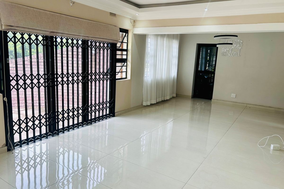Spacious, light-filled living area featuring polished porcelain floor tiles, recessed ceiling with downlights, and secure sliding door access to the exterior.