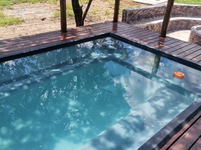 A private plunge pool set into a timber deck, featuring a surrounding timber railing and adjacent built-in stone seating area.