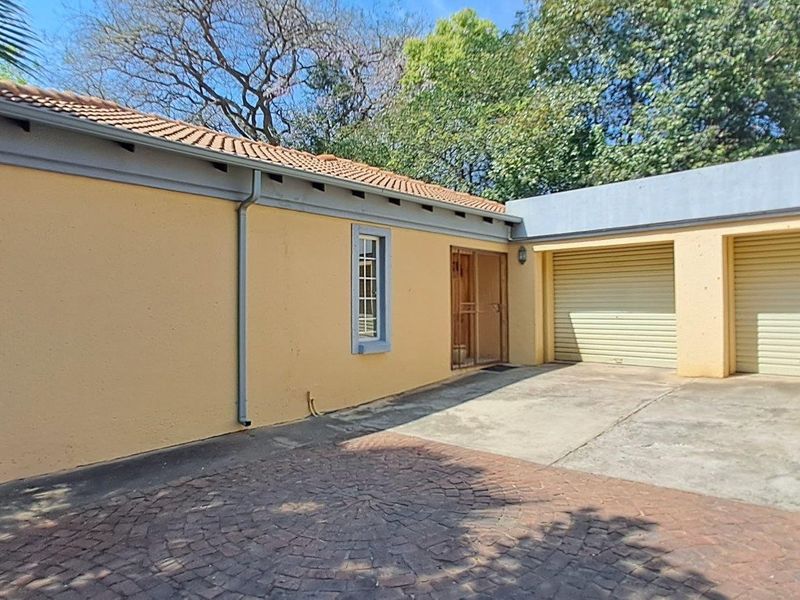 Exterior view of the property featuring a double garage with roller shutter doors, a paved driveway, and a tiled roof.