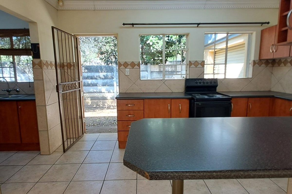Functional kitchen featuring wood-finish cabinetry, tiled backsplash, and direct access to the exterior via a security gate.