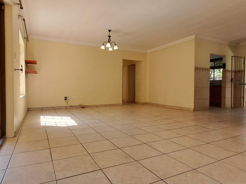 Spacious open-plan living and kitchen area featuring tiled flooring, neutral walls, and direct access to an outdoor patio through sliding glass doors.