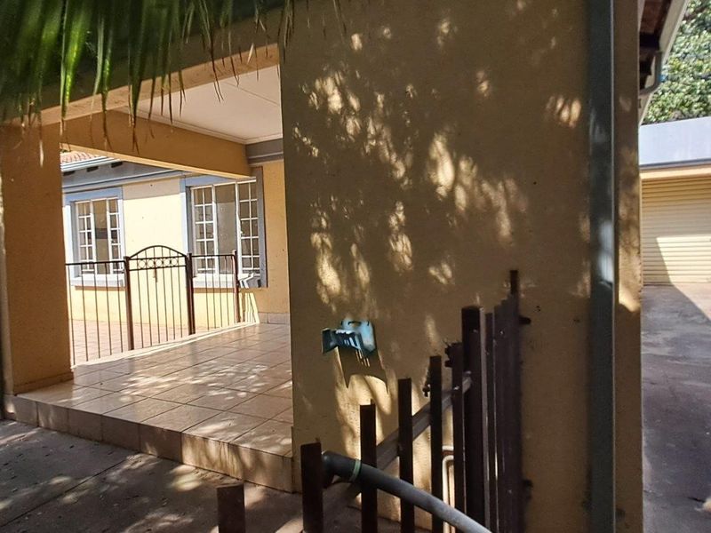 Covered patio area overlooking the swimming pool, featuring tiled flooring and adjacent access to the garage and driveway.