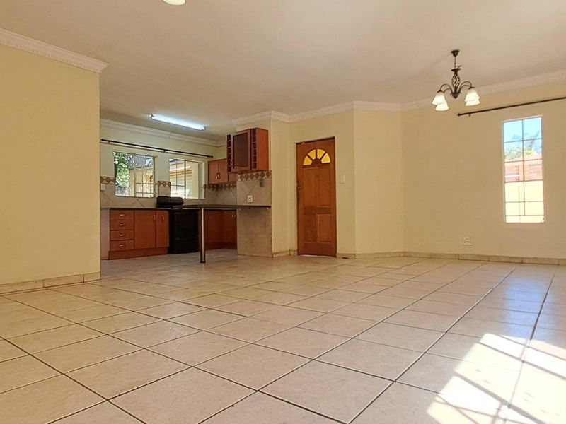 Spacious open-plan living and kitchen area featuring tiled flooring, coved cornicing, and direct access to the outdoors via sliding glass doors.