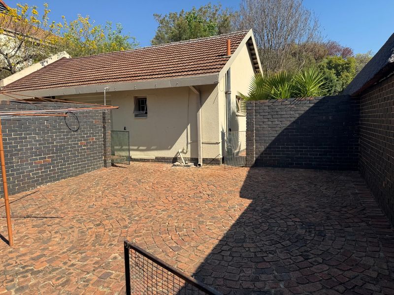 A private rear courtyard featuring decorative brick paving, enclosed by solid brick boundary walls and adjacent to the main building structure.