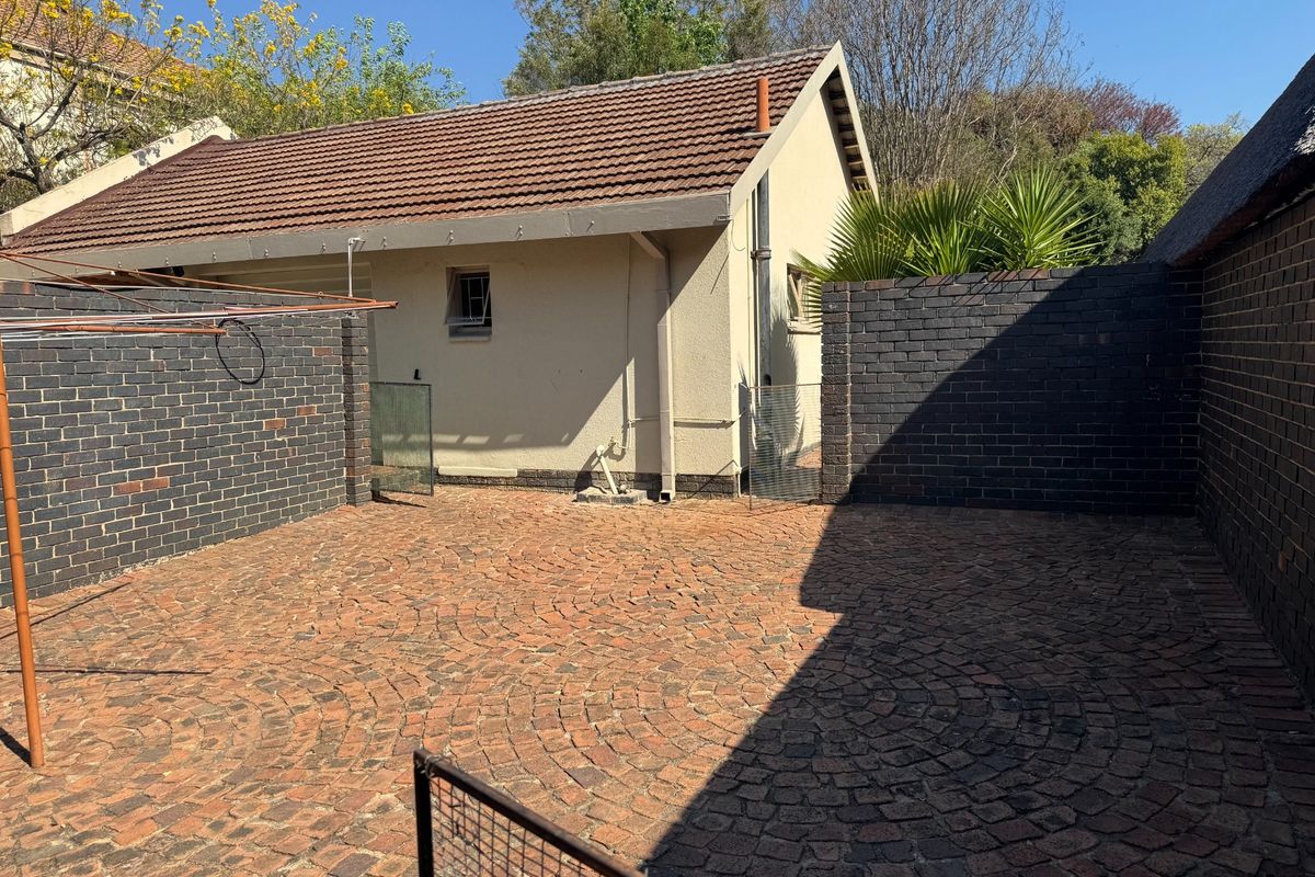 A private rear courtyard featuring decorative brick paving, enclosed by solid brick boundary walls and adjacent to the main building structure.