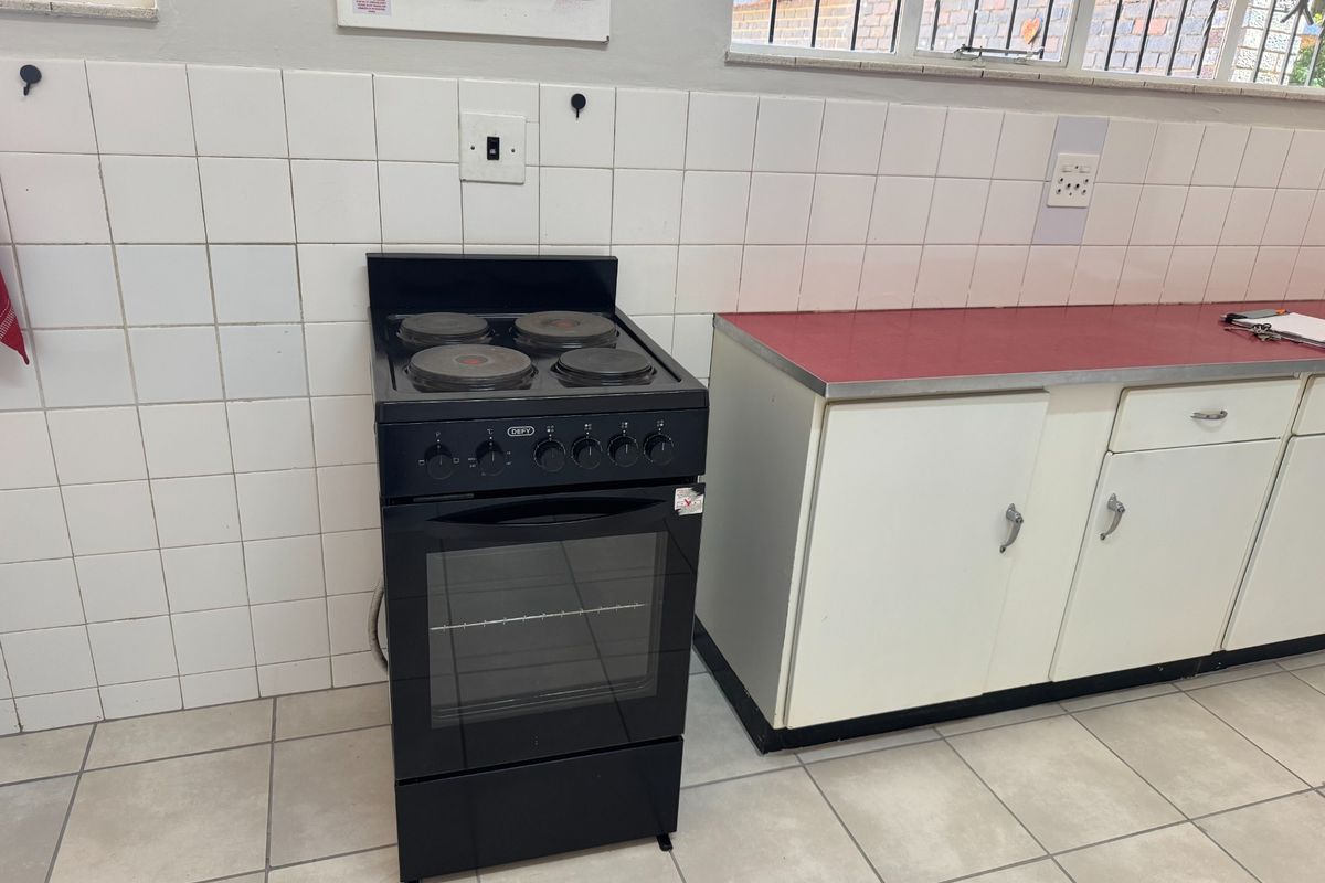 A functional kitchen area featuring a freestanding stove, tiled splashback, laminate countertops, and built-in cabinetry with tiled flooring.