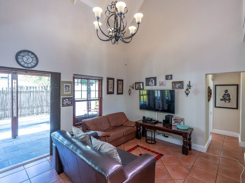 Spacious living room featuring a high vaulted ceiling, terracotta floor tiles, and a sliding glass door providing direct access to the outdoor patio area.