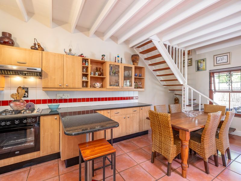 Open-plan kitchen and dining area featuring light wood cabinetry, granite countertops, gas hob, and a staircase leading to the upper level.