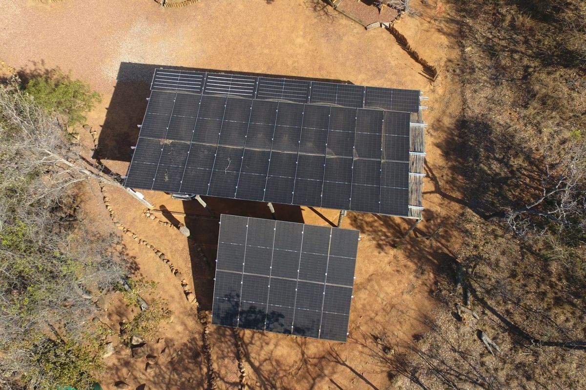 Aerial view of a ground-mounted solar panel array installation situated in a rural outdoor setting.