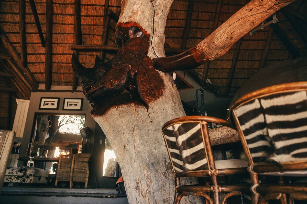 A unique living space featuring a high thatched roof with exposed timber rafters and a prominent central carved wooden pillar.