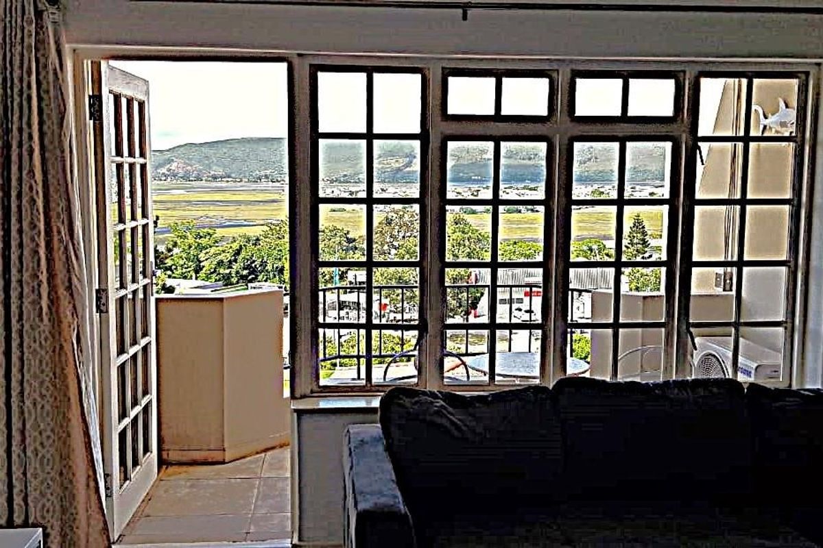 Living room featuring large grid-pattern windows and french doors opening onto a balcony with scenic landscape views.