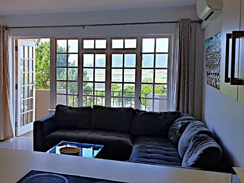 Open-plan living area featuring a split-system air conditioner, large multi-pane windows, and direct access to a balcony with scenic views.