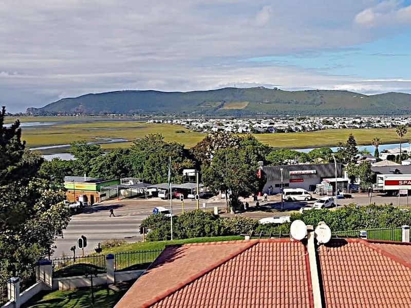 Elevated view overlooking the surrounding neighborhood, local commercial area, and scenic wetlands with distant mountains.