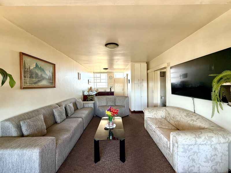 A spacious living room featuring neutral walls, carpeted flooring, and built-in storage cupboards, offering a functional and comfortable layout.
